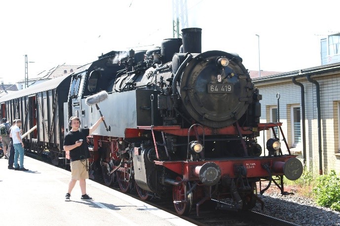 Sounddesigner Maurice Schill mit Aufnahme-Kit, vor der historischen Dampflok der Schwäbischen Waldbahn